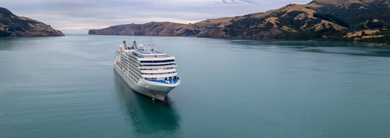 Silversea cruise ship sailing through a scenic fjord with dramatic terrain