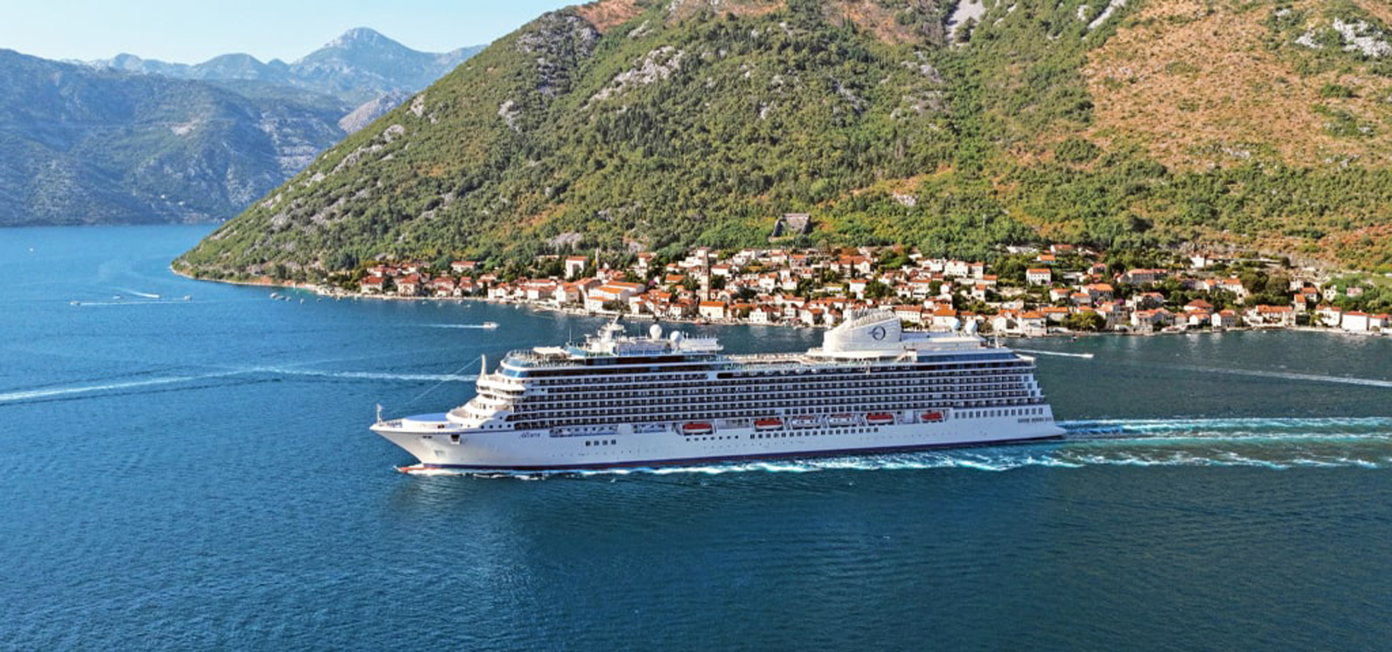 Cruise Ship in Scenic Coastal Mediterranean Town Oceania cruise ship sailing through crystal-clear Mediterranean waters near a charming coastal town