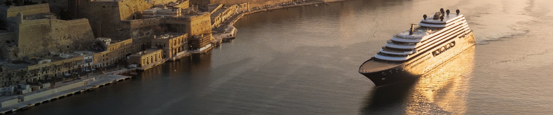 Luxury Ritz-Carlton yacht docked in a Mediterranean harbor at golden hour