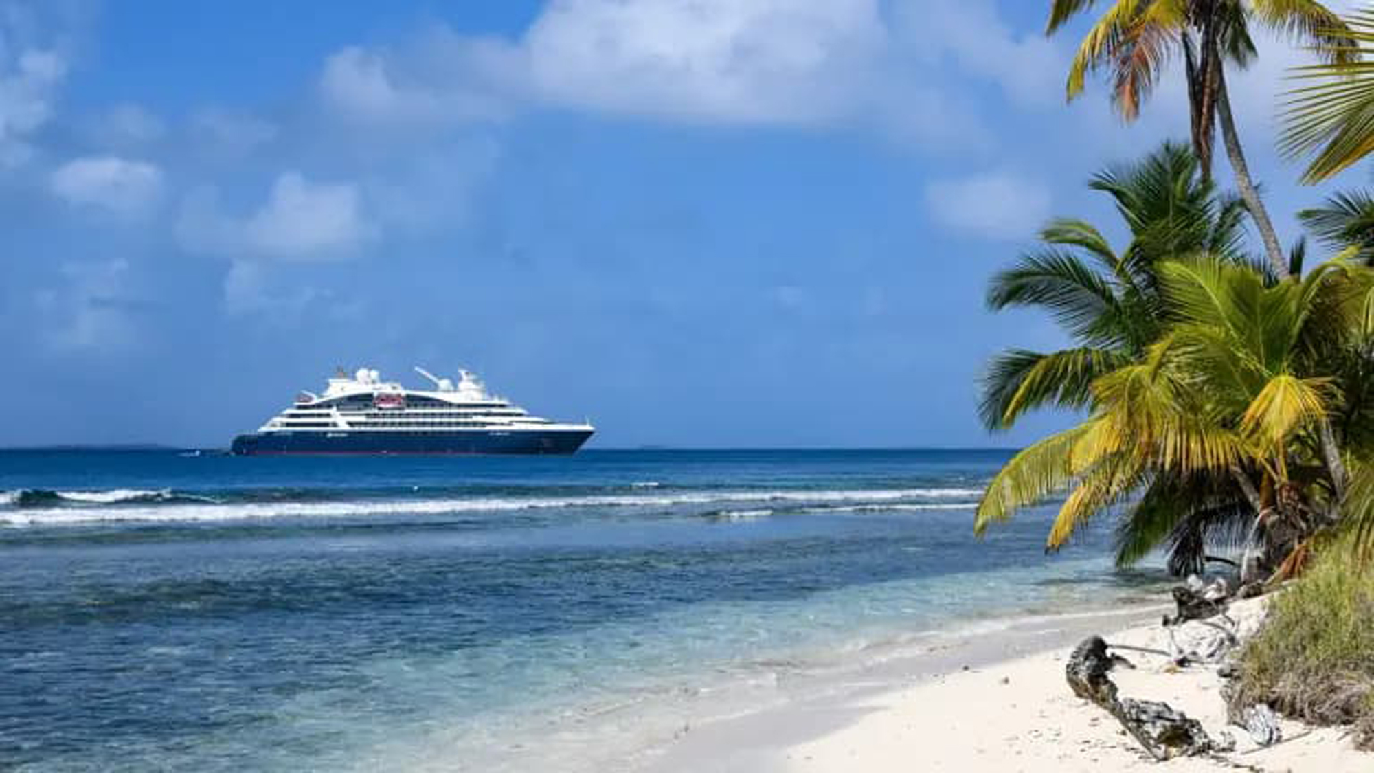 Luxury Cruise Ship by Tropical Beach Ponant luxury cruise ship anchored near a tropical beach with crystal clear waters