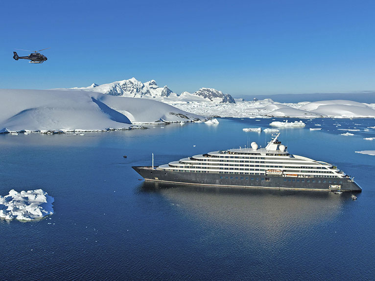 A sleek, modern cruise ship navigating through icy blue waters surrounded by snow-covered mountains
