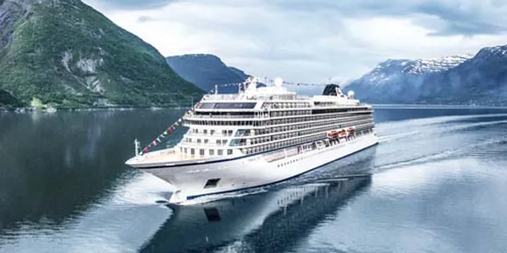 A pristine white cruise ship sailing through a serene fjord surrounded by majestic green