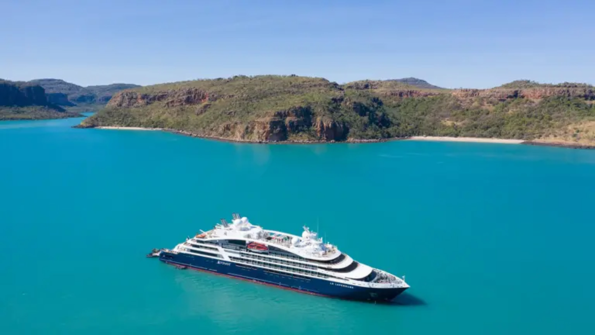 Luxury Cruise Ship in Turquoise Waters A sleek, modern cruise ship anchored in stunning turquoise waters near a rugged, green coastal