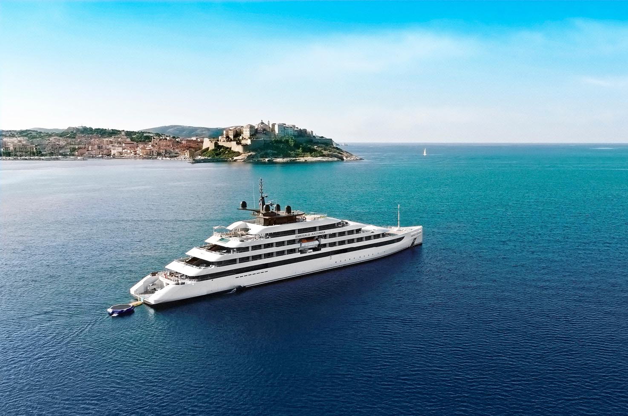 Emerald Azzurra luxury yacht anchored near a historic coastal Mediterranean town