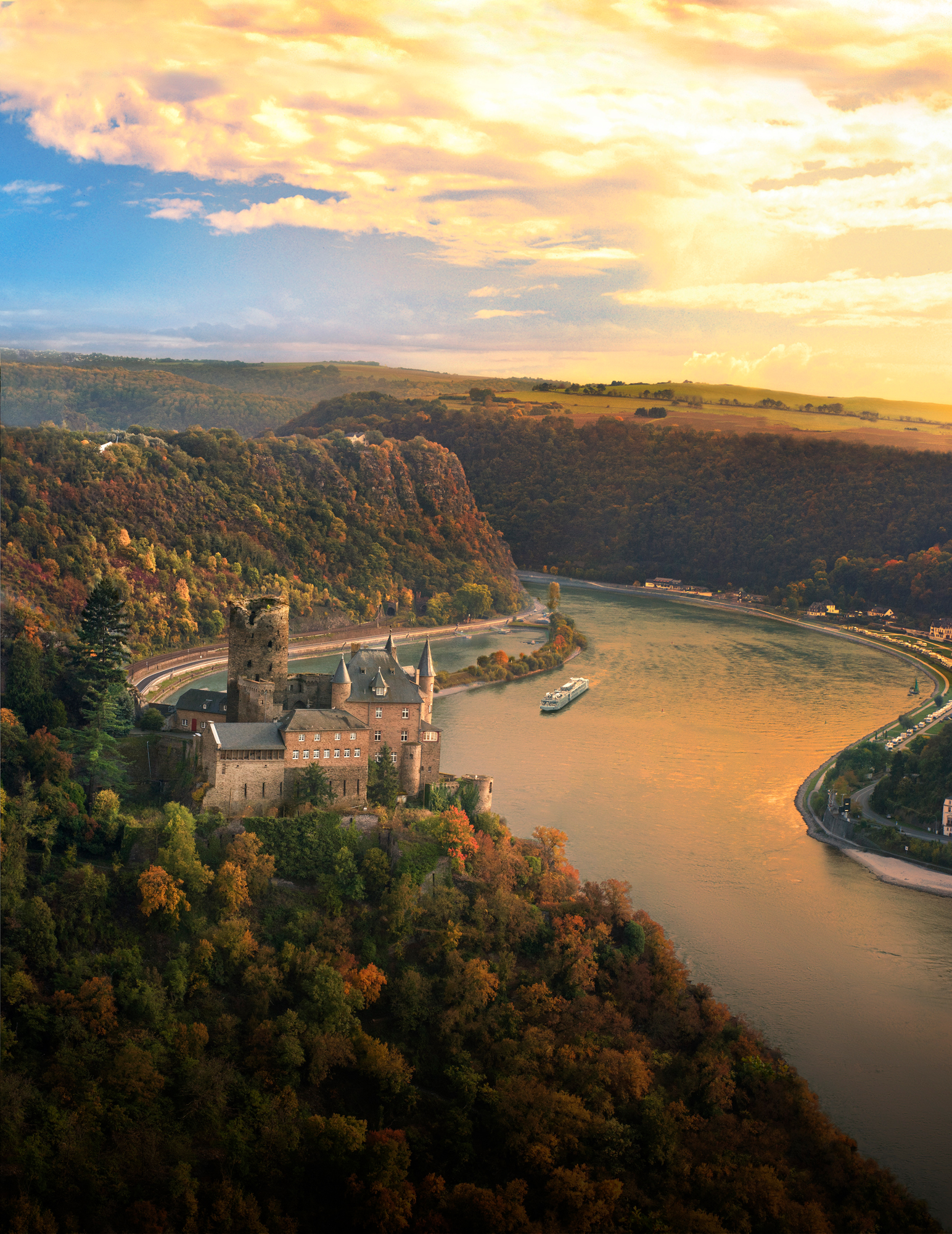 Medieval Castle on Rhine River Bend A historic stone castle perched on a forested riverbank with a dramatic curved river and golden
