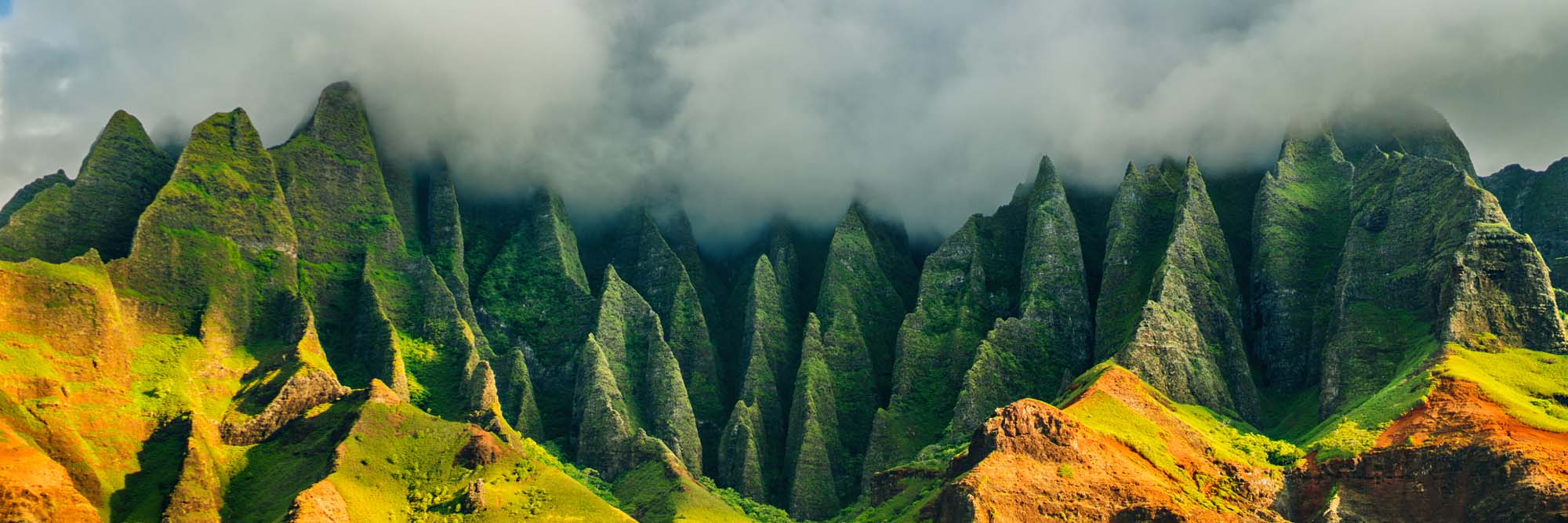 Na Pali Coast Jagged Mountain Peaks Dramatic mountainous coastline with sharp, green-covered peaks rising dramatically against a misty cloudy background, showcasing the rugged terrain of Kauai, Hawaii.