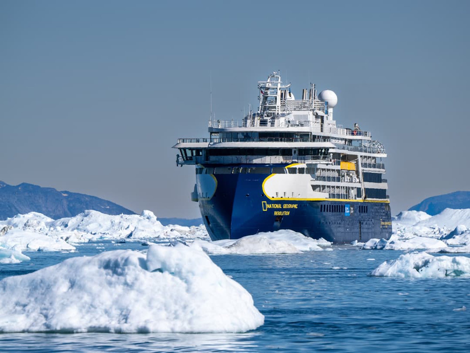 National Geographic Resolution navigating through icebergs and pack ice in Antarctica with snow-covered mountains