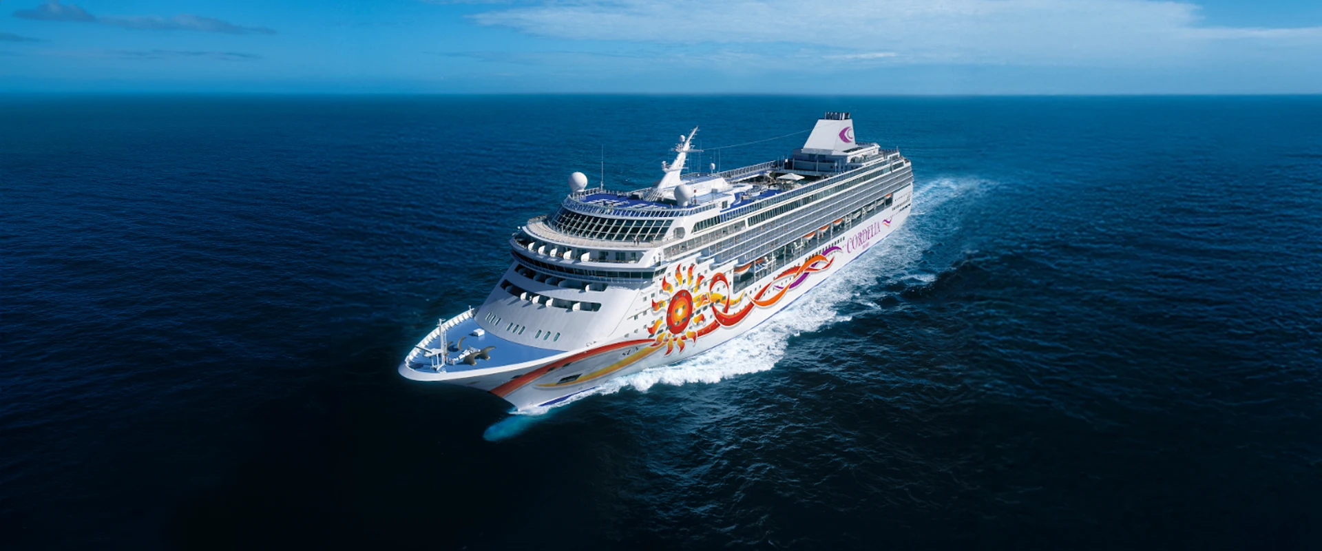 Norwegian Cruise Ship Sailing Blue Ocean A colorful cruise ship with a vibrant sun-like graphic design sailing across deep blue waters under