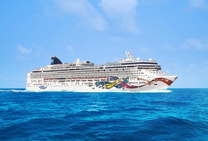 Norwegian Cruise Ship in Bright Blue Waters A colorful Norwegian Cruise Line ship sailing on turquoise blue ocean waters under a clear sky