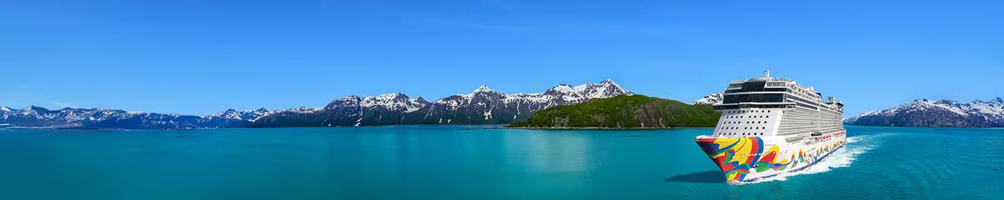 Norwegian Cruise in Alaskan Scenic Landscape A colorfully decorated cruise ship sailing through turquoise waters with snow-capped mountain