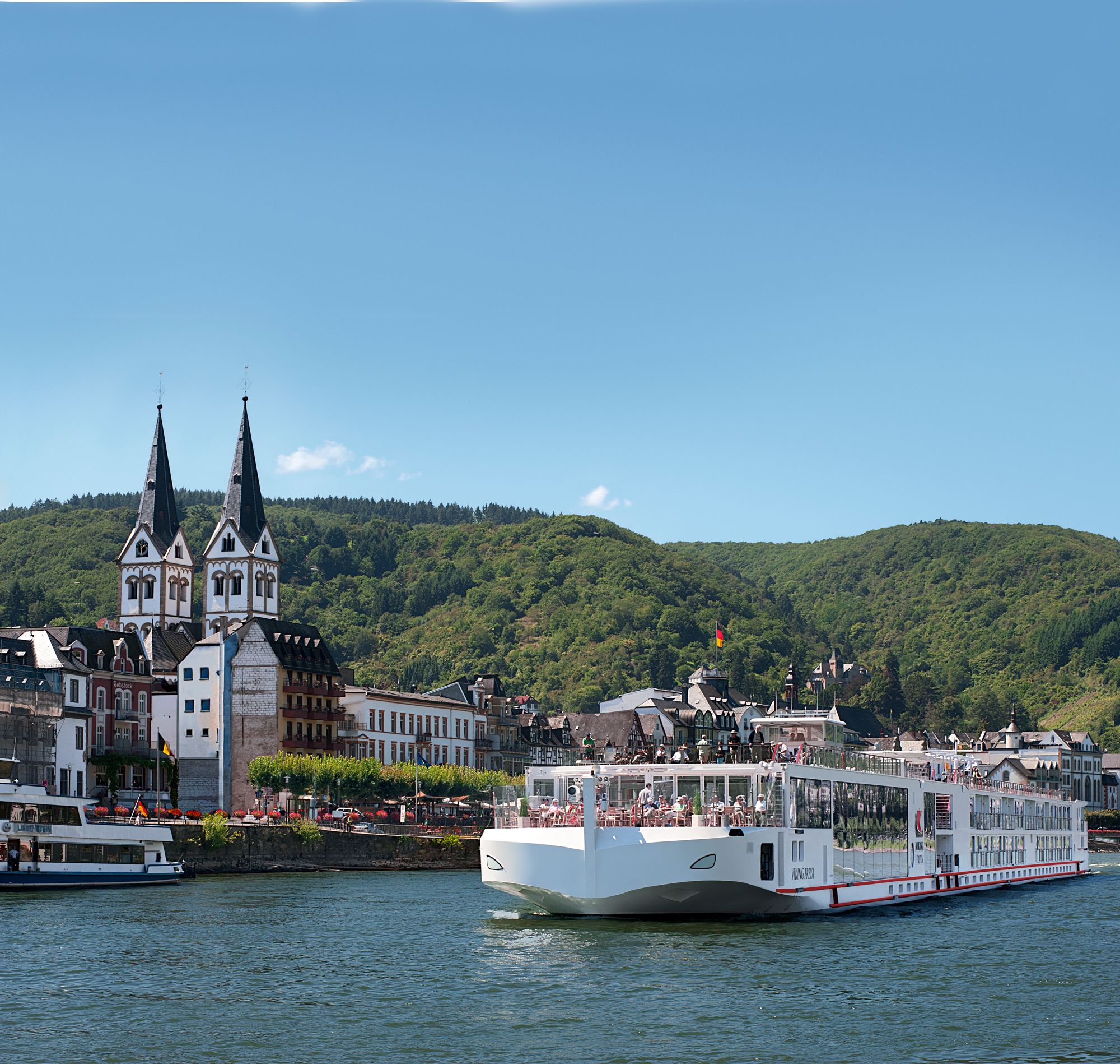 River Cruise Along the Moselle in Germany A white river cruise ship docked in a picturesque German town with twin-spired church towers