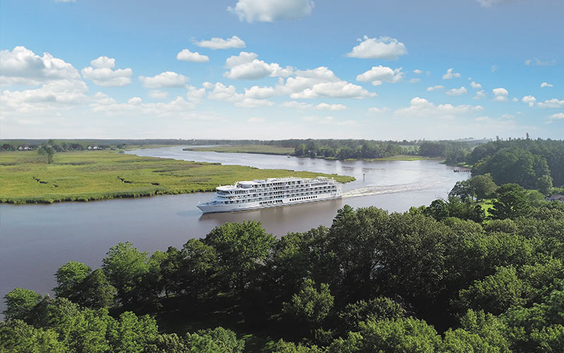 River Cruise Ship Sailing Through Lush Landscape A white river cruise ship navigates through a wide river surrounded by green forests and grassy plains under a blue sky