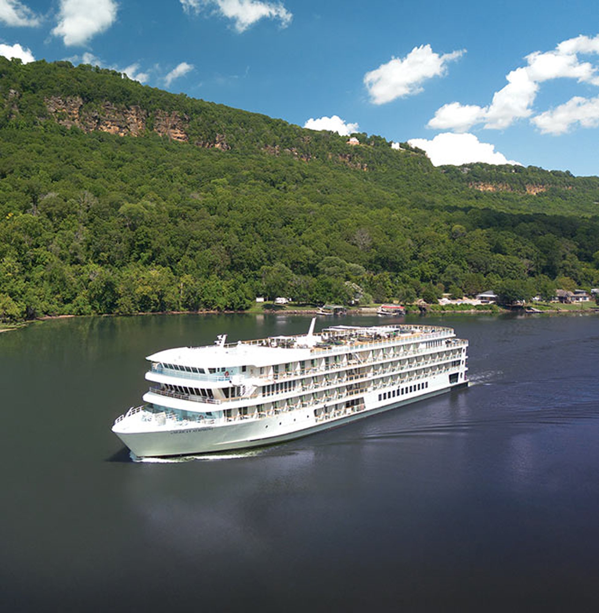 River Cruise Ship on Scenic Waterway A large white river cruise ship navigates a calm river flanked by lush, densely forested hillsides