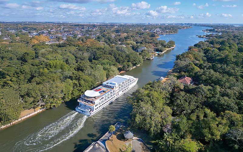 River Cruise Through Lush Landscape A large white river cruise ship navigating through a verdant waterway surrounded by dense trees