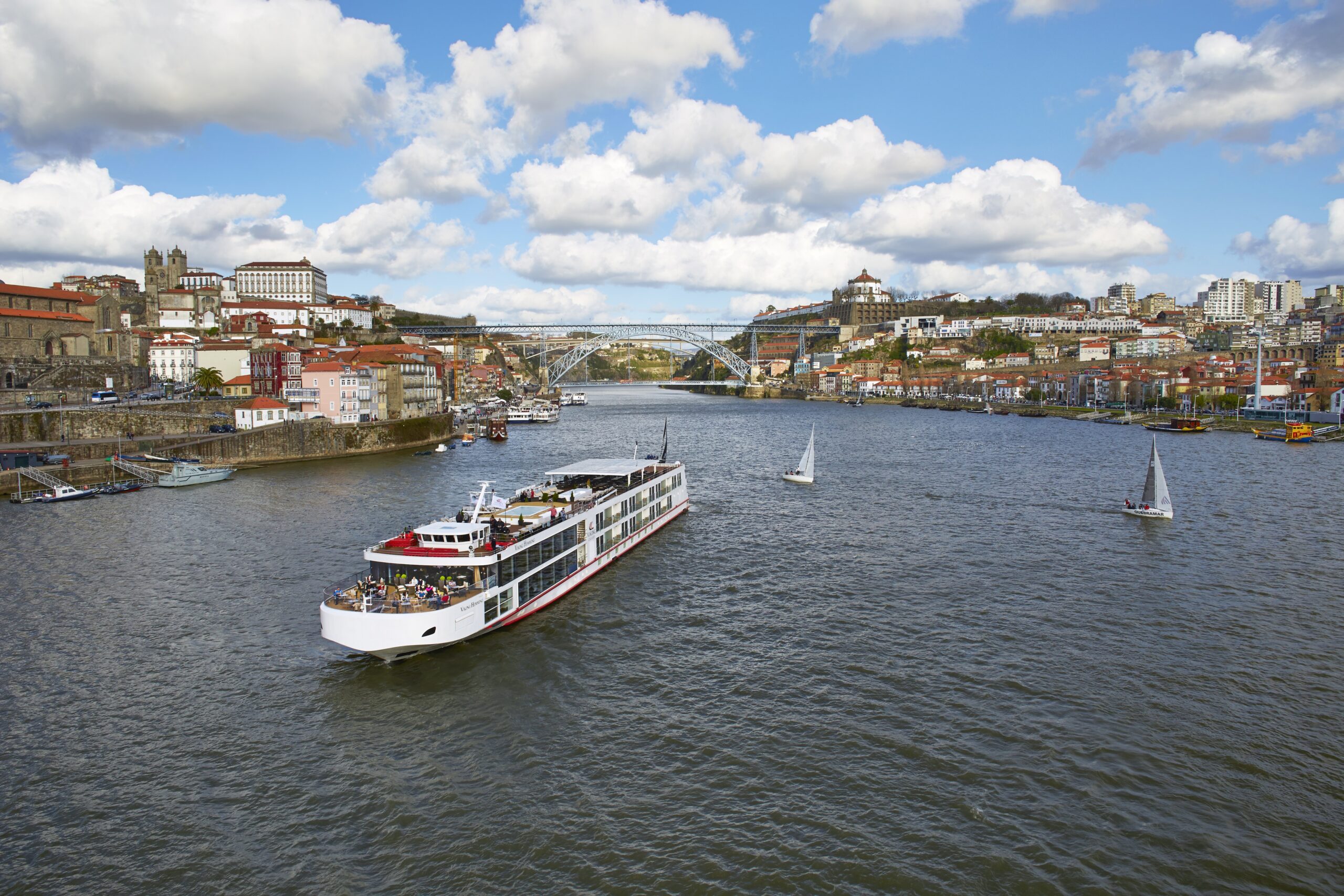 Viking River Cruise Ship in Porto A modern river cruise ship navigates the Douro River in Porto, with the iconic Dom Luis I Bridge and historic city architecture in the background.