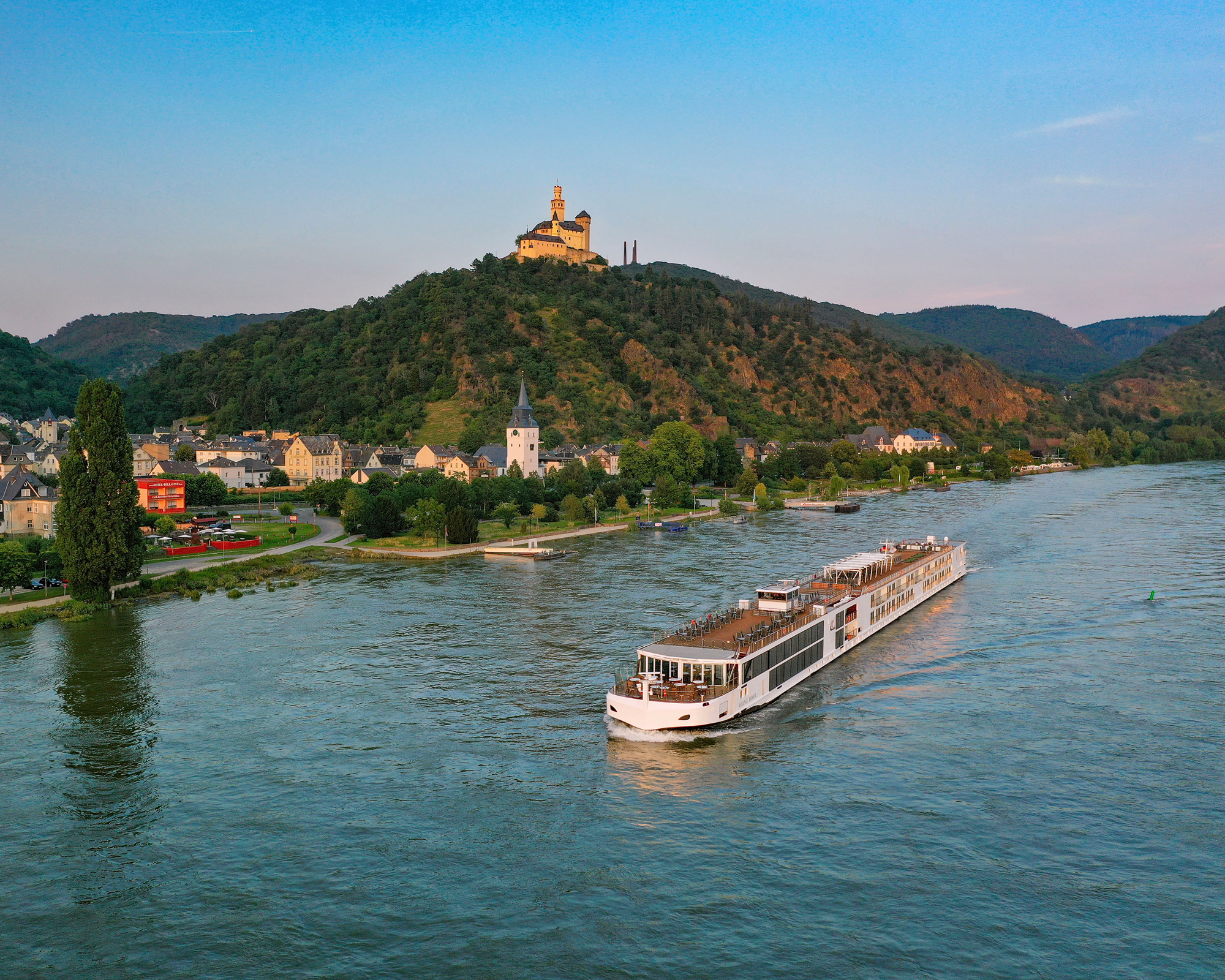 River Cruise on the Moselle in Germany A modern river cruise ship sailing along the Moselle River, with a picturesque medieval castle