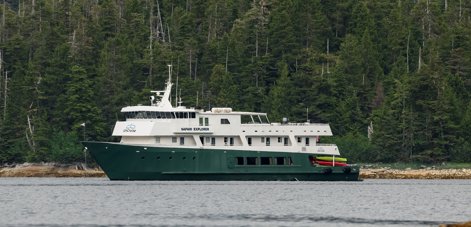 Safari Explorer Expedition Cruise Ship Safari Explorer expedition cruise ship anchored near evergreen forest coastline with colorful kayaks