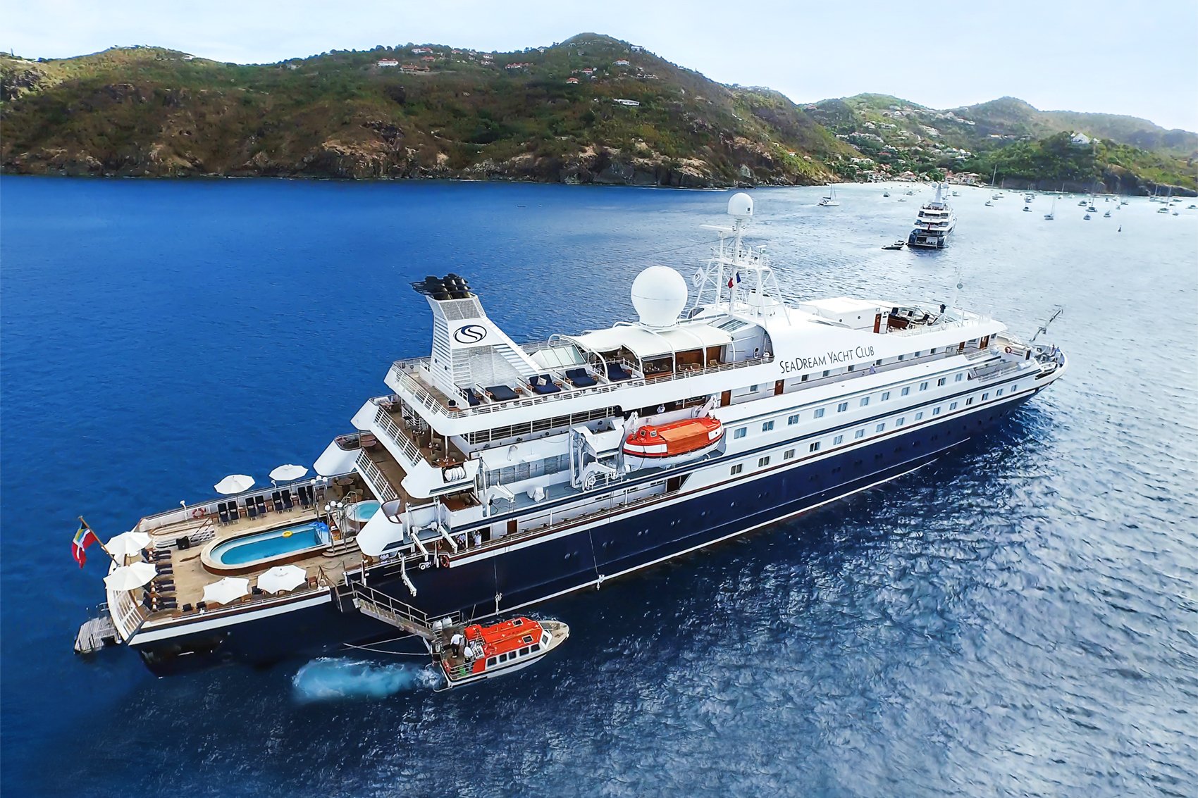 SeaDream yacht anchored in a picturesque Mediterranean bay with lush green hills