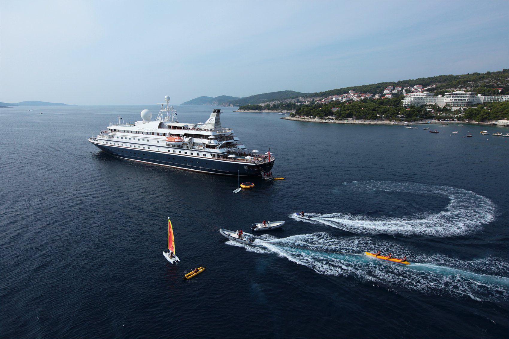 SeaDream yacht navigating through a dramatic fjord with steep green mountainsides