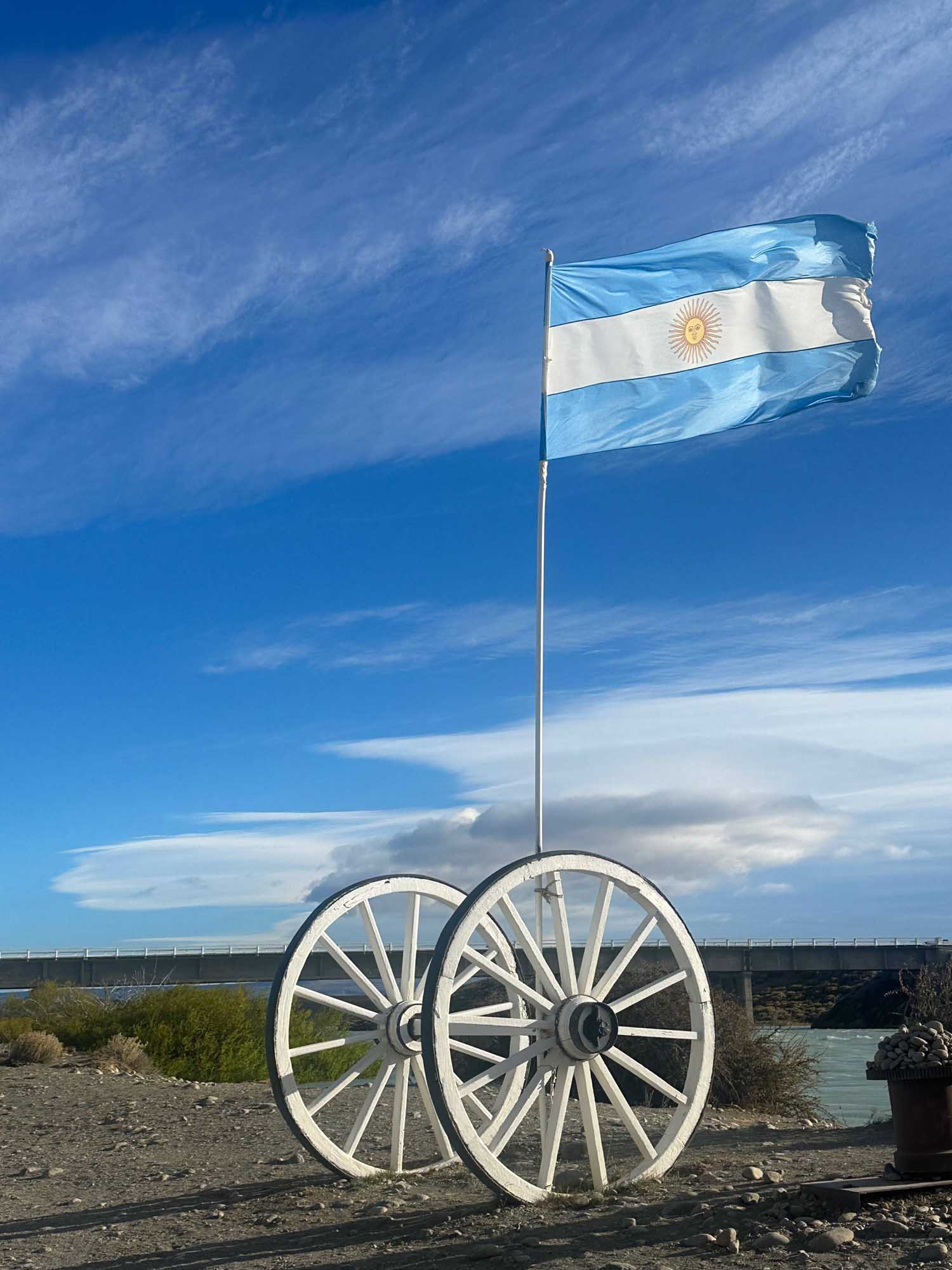 Argentine Flag on Historic Wagon The Argentine flag flies proudly from a flagpole mounted on a pair of white wooden wagon wheels