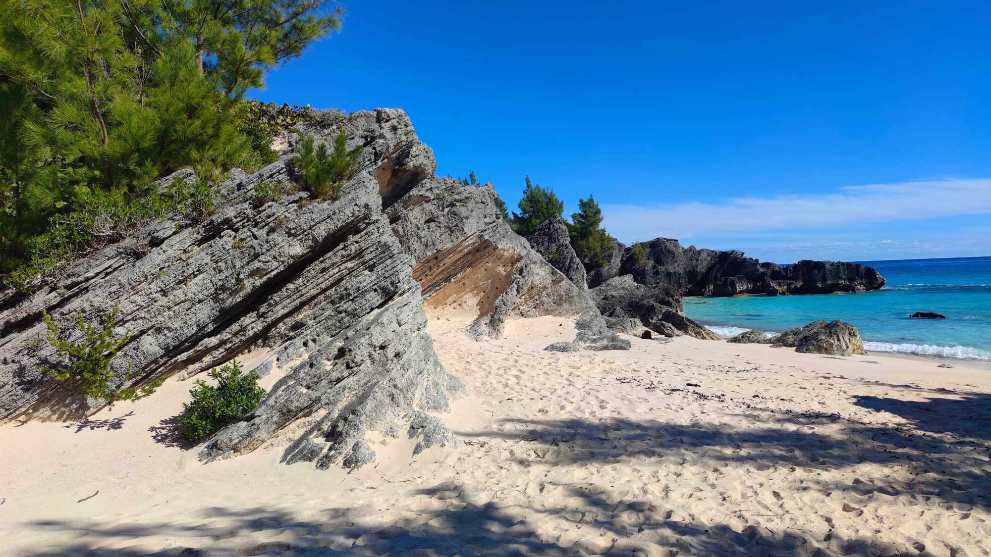 Bermuda Tropical Beach with Rocky Outcrops A pristine tropical beach in Bermuda featuring distinctive layered pink and gray rock formations