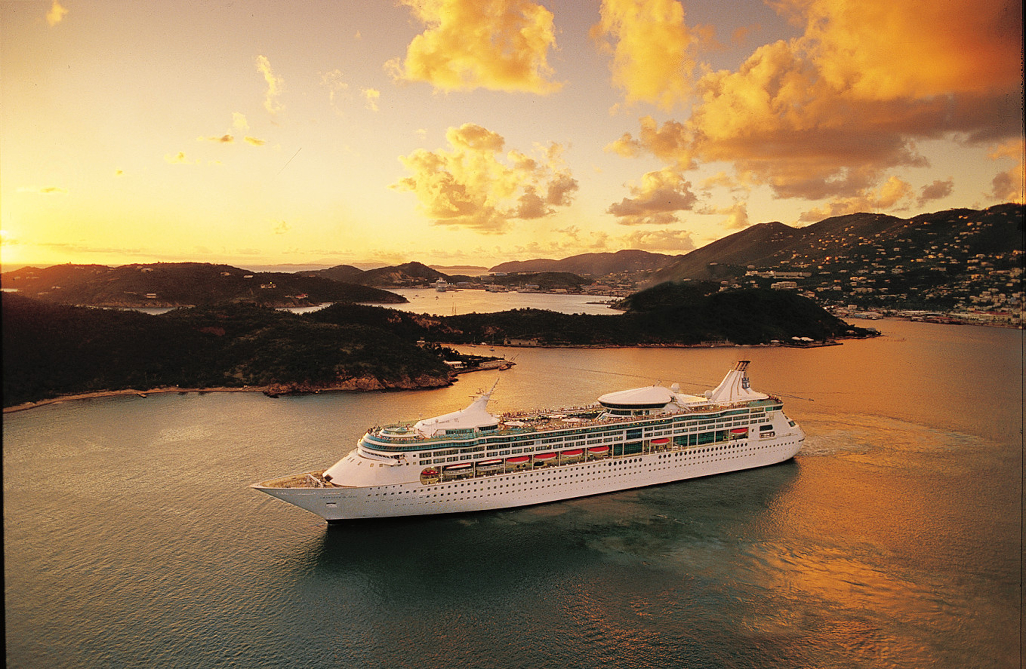 Rhapsody of the Seas Anchored at Caribbean Sunset A large Royal Caribbean Vision-class cruise ship anchors in calm turquoise waters surrounded