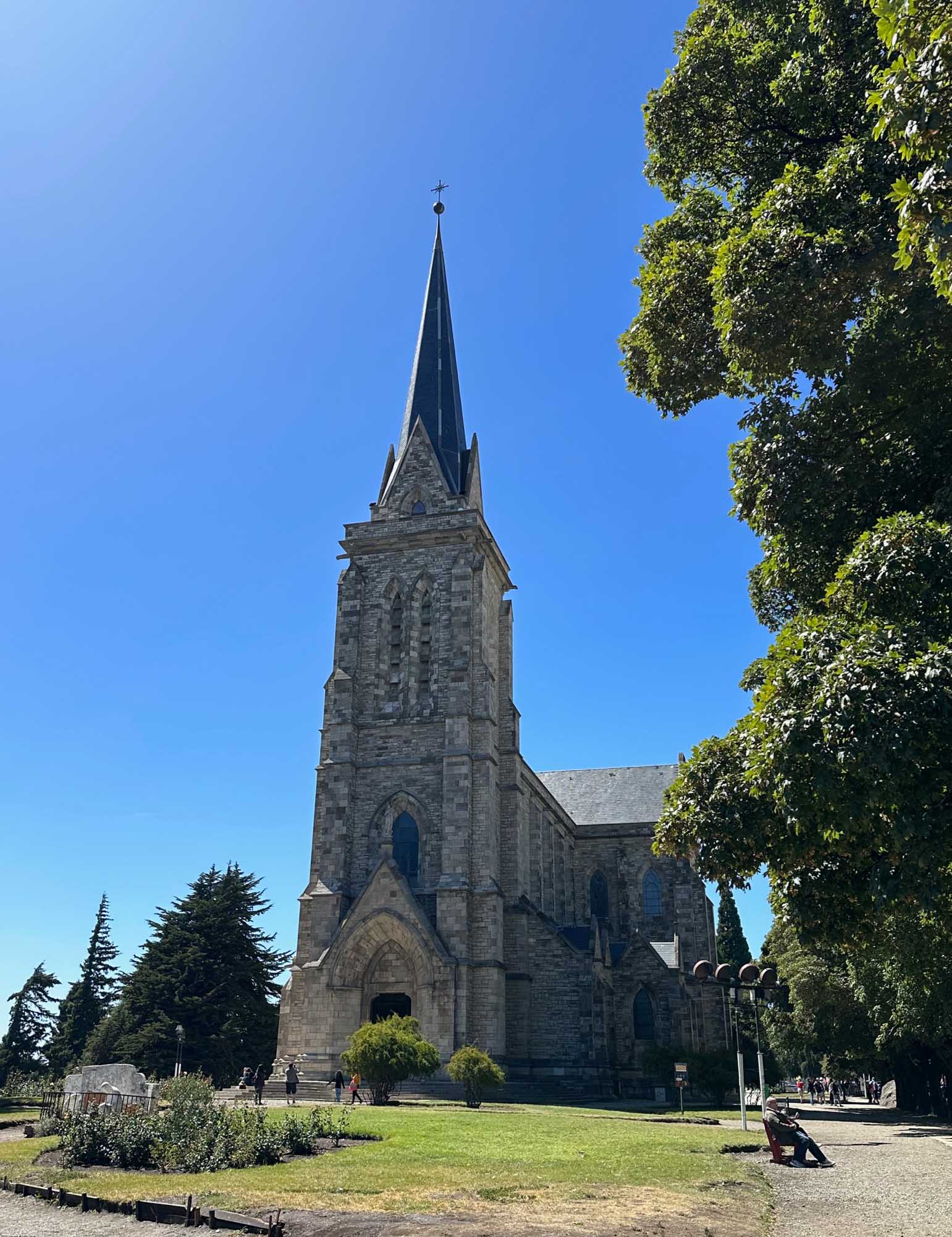 Historic Stone Church with Spire in Patagonia A striking Gothic Revival stone church with a tall pointed spire topped by a cross stands