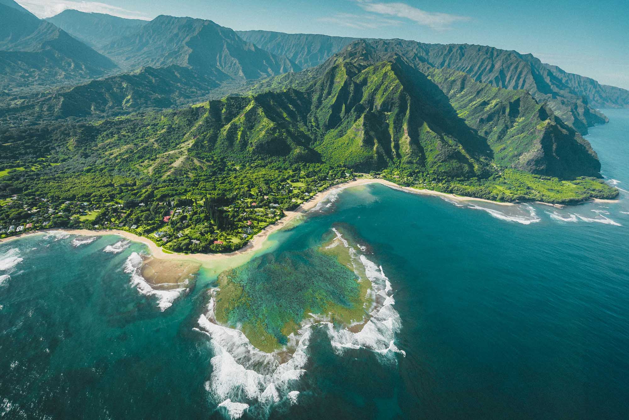 Kalalau Valley Aerial View, Kauai Hawaii An aerial photograph of the lush Kalalau Valley on Kauai's dramatic Na Pali Coast, featuring verdant cliffs, a pristine sandy beach, turquoise waters, and white-capped ocean waves. The steep fluted pali (cliffs) rise majestically from the valley floor, showcasing the island's stunning volcanic geology and tropical vegetation.