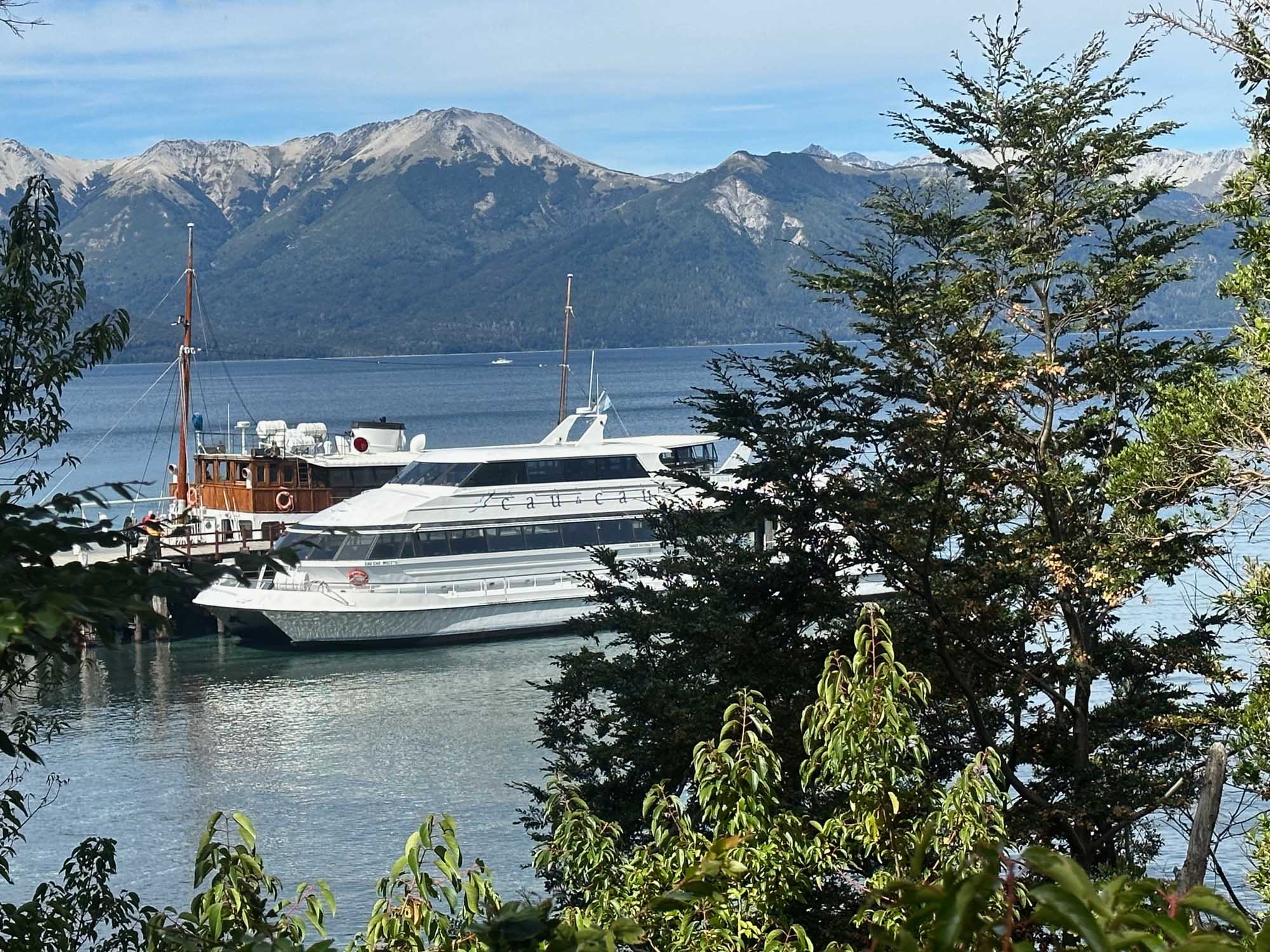 Luxury Cruiser Moored in Alpine Lake A modern multi-deck cruise vessel and traditional wooden sailing ship are moored in a pristine