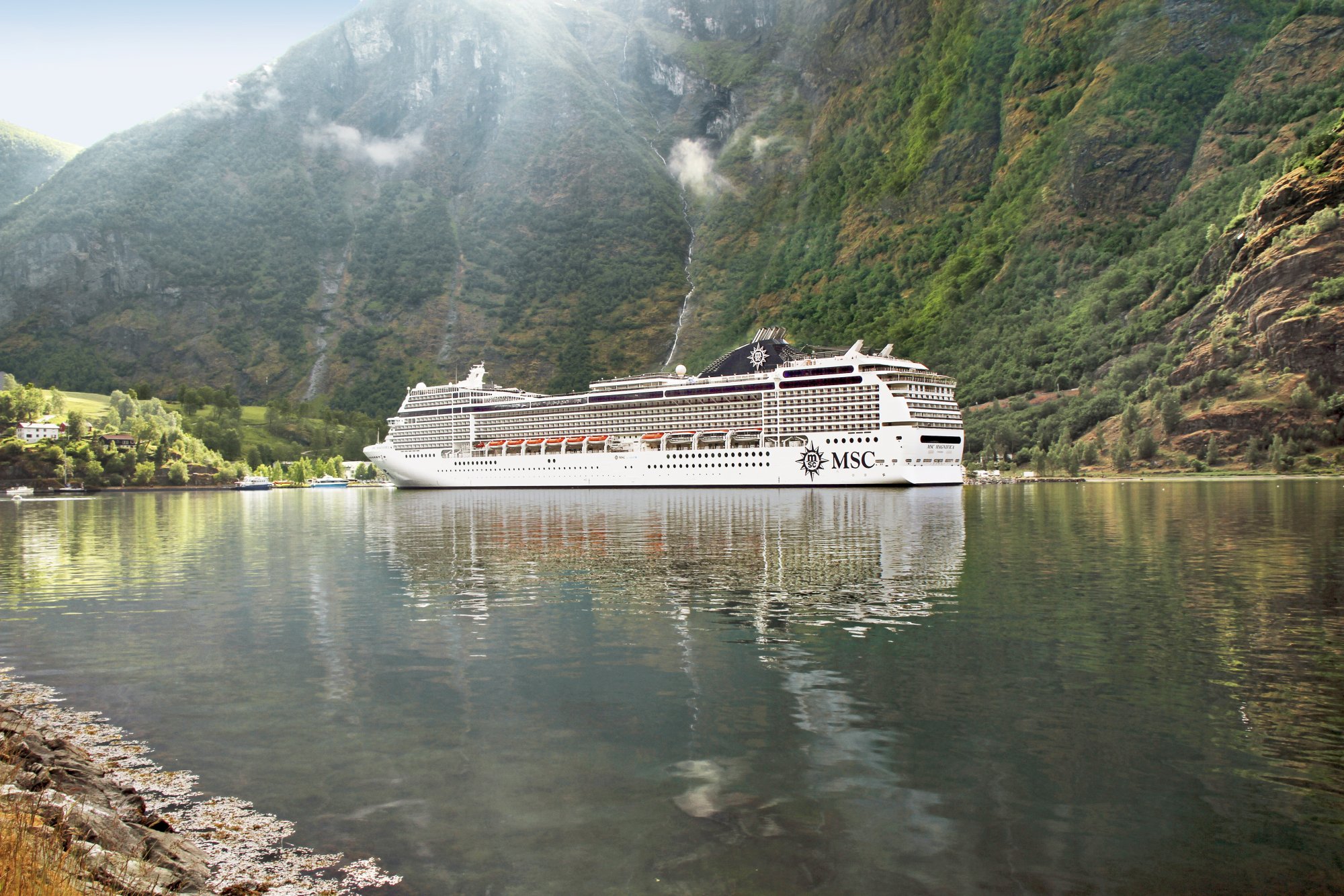 MSC cruise ship sailing through a dramatic Norwegian fjord surrounded by steep mountains