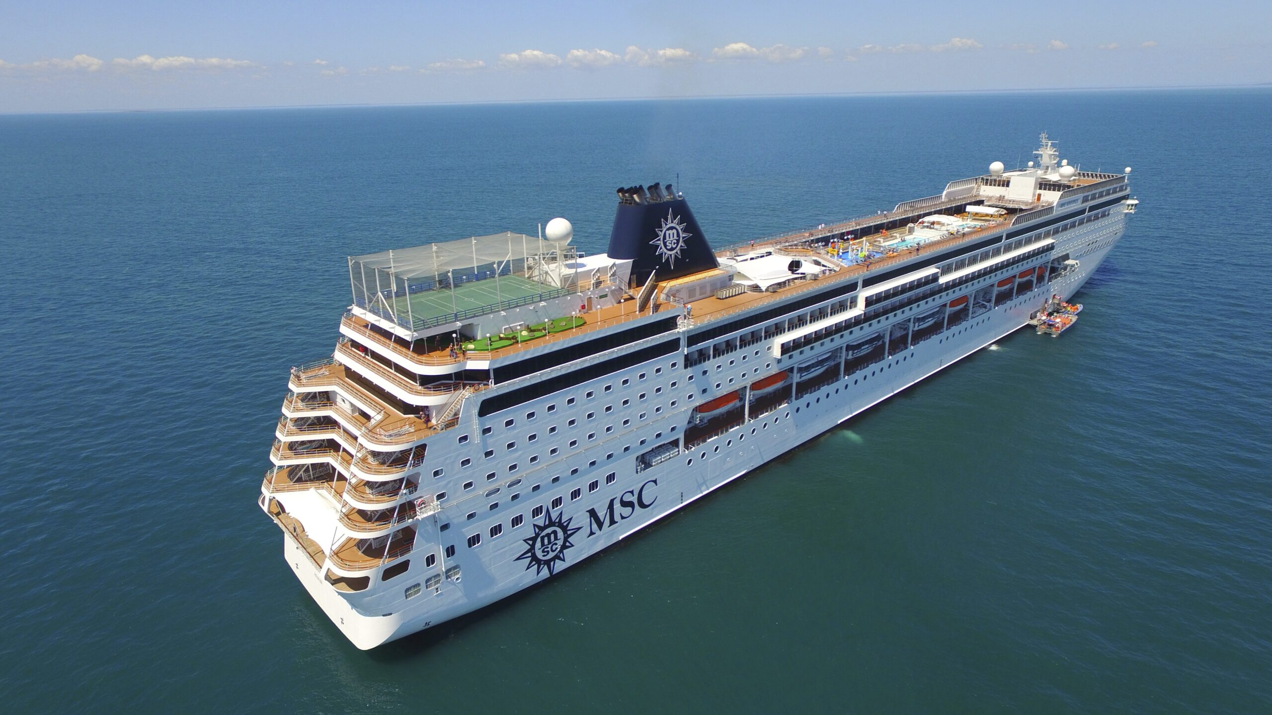 A modern cruise ship with distinctive MSC branding on the hull, photographed from an aerial