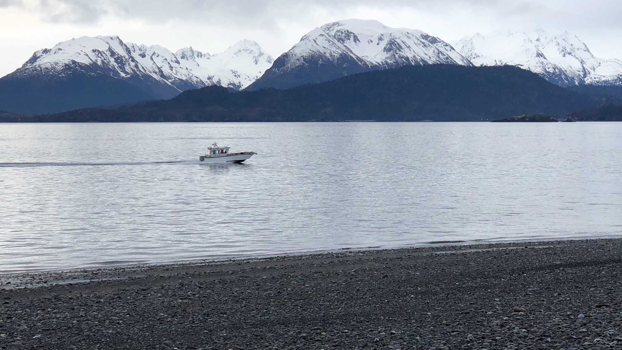 Snow-Capped Mountains and Boat in Patagonian Lake A serene Patagonian landscape featuring a small fishing or tour boat anchored in calm waters