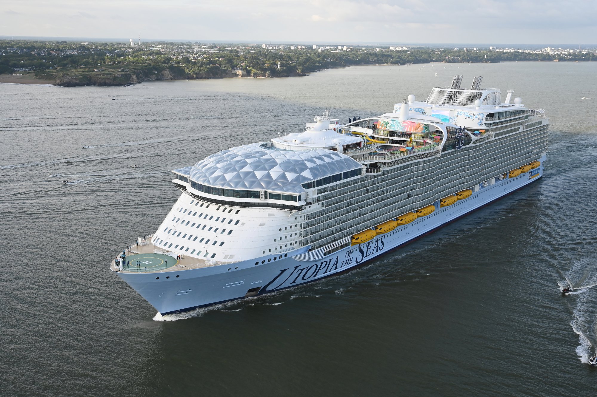 Utopia of the Seas cruise ship with distinctive light blue hull anchored in coastal waters