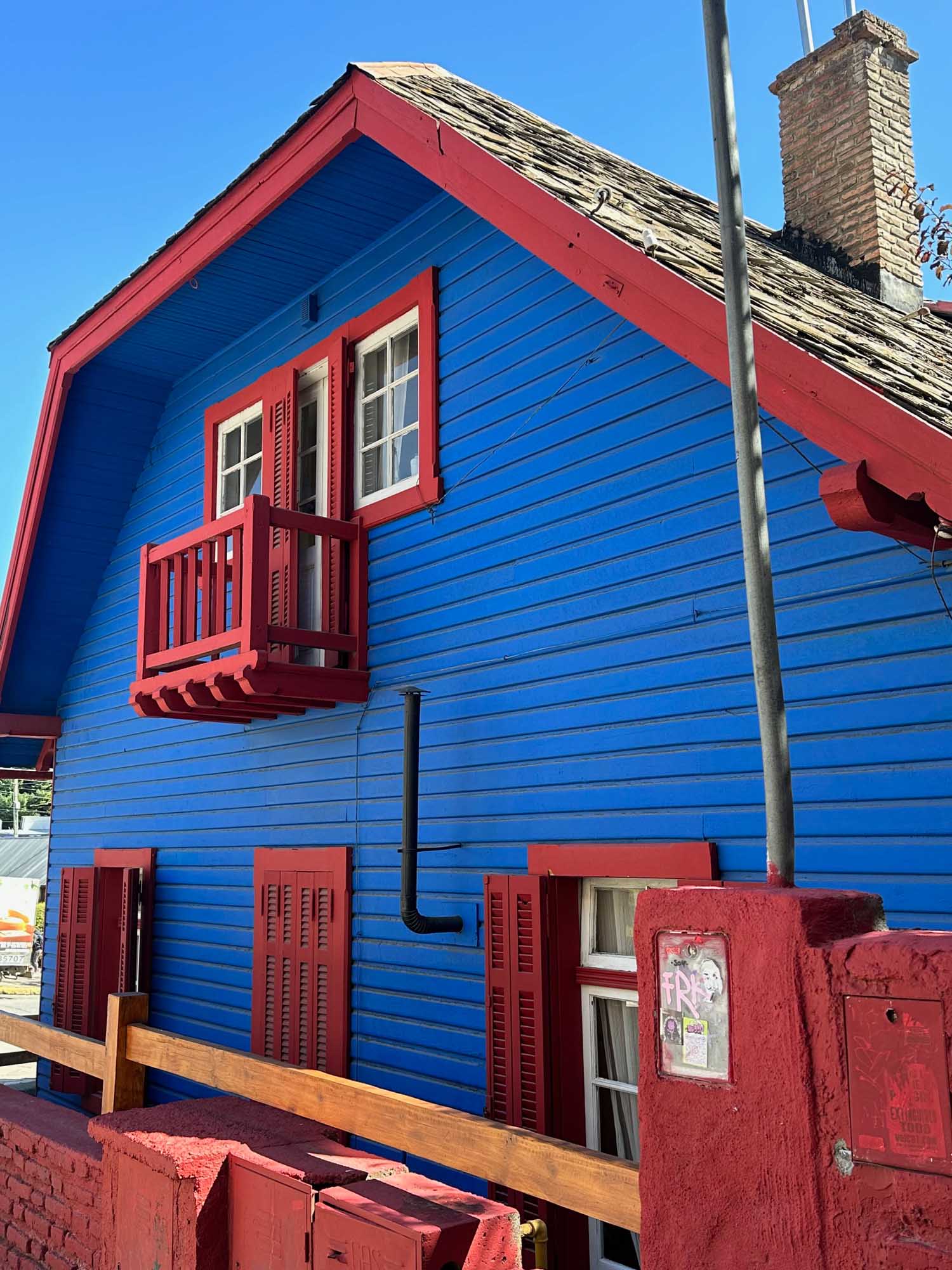 Vibrant Blue and Red Beachside House A striking residential building painted in bold blue with bright red trim and accents, featuring