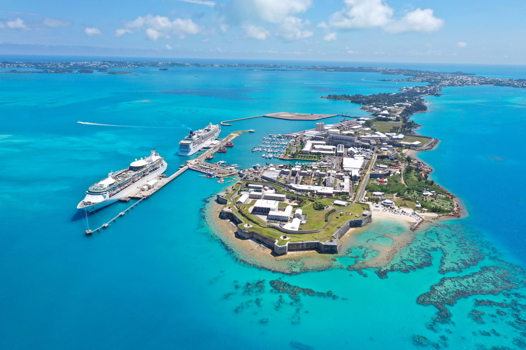 adobestock-778287167 An aerial view of a large cruise ship docked at King's Wharf in Bermuda, showcasing the iconic fortress and colonial architecture alongside turquoise waters.