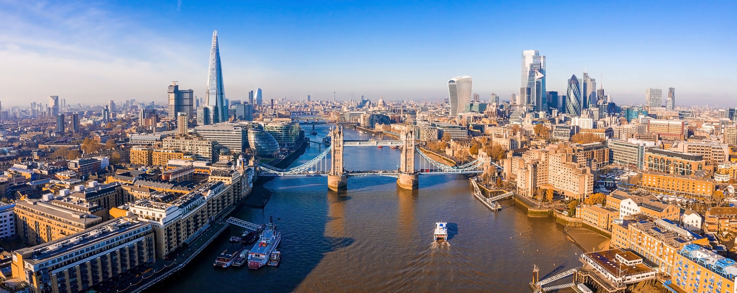 An expansive aerial view of London's iconic skyline featuring Tower Bridge spanning the River