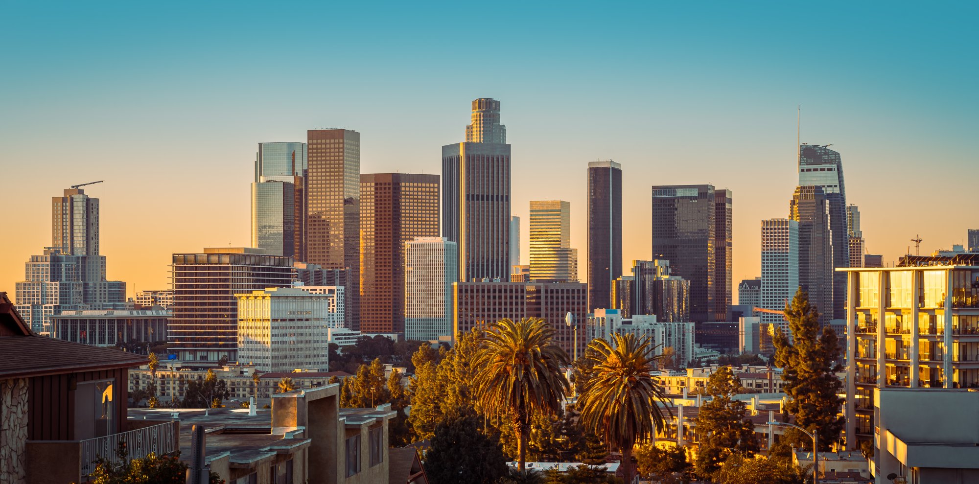 A stunning view of downtown Los Angeles skyline bathed in warm golden sunlight during sunset