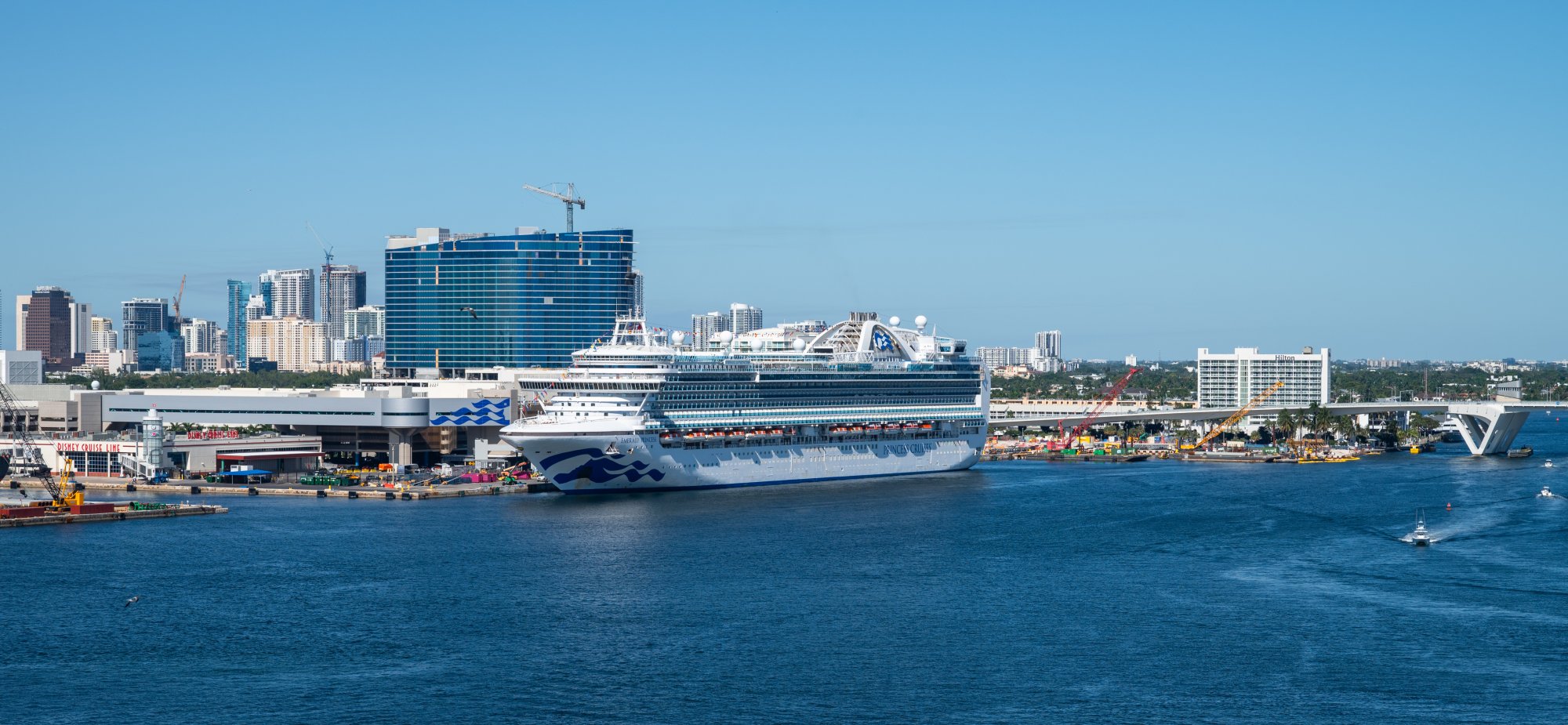 A large contemporary cruise ship with distinctive blue hull design is docked at Port Everglades