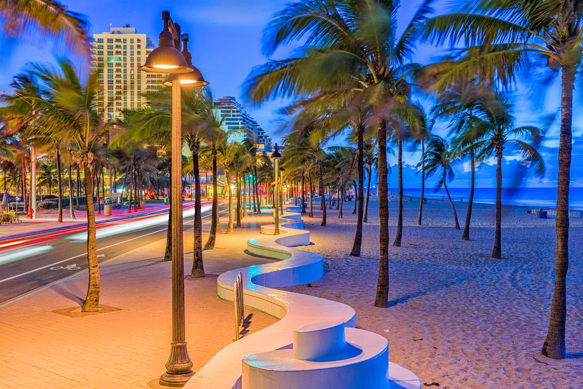 A scenic twilight view of Fort Lauderdale's beachfront promenade featuring illuminated street